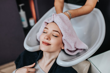 Wall Mural - Professional hairdresser washing hair of a beautiful young  woman in hair salon. .