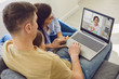 © Studio Romantic - Online medical consultation for family patients. Doctor woman video call using laptop talks with family sitting on the sofa at home.