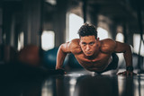 Fototapeta  - Muscular and strong athletic man doing Push up exercising in sport gym.