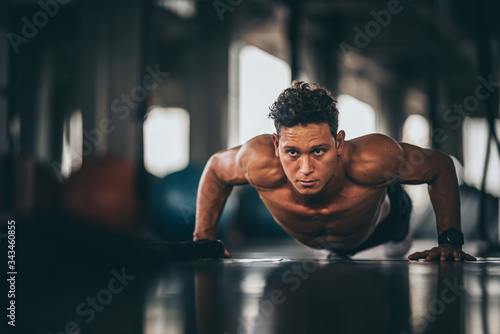 Fotografía Muscular and strong athletic man doing Push up exercising in sport gym