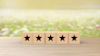 © Andrea - Wooden cube five black star review on blur field of flowers background. Service rating, satisfaction concept. reviews and comments google maps, tripadvisor, facebook. online evaluations.