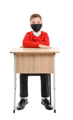 Sticker - Little schoolboy in protective mask sitting at desk on white background. Concept of epidemic