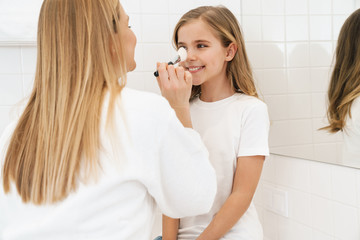 Wall Mural - Photo of mother and daughter smiling while doing makeup in bathroom