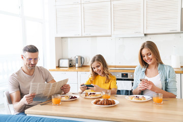 Wall Mural - Photo of family using smartphones while having breakfast