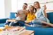© Drobot Dean - Photo of cheerful family eating popcorn and pizza while watching tv