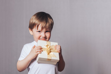 Canvas Print - Beautiful little boy in a white T-shirt holding a gift in his hand, mother's day, Valentine's day, March 8, birthday