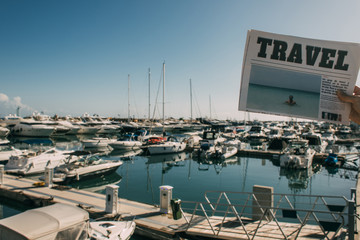 Wall Mural - cropped view of woman holding travel newspaper near docked ships in mediterranean sea