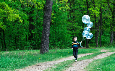 boy with balloons in the green forest