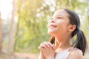 Wall Mural - cute little girl hands praying to god with the bible in the morning on nature background.  little asian girl hand praying for thank god. copy space. spirituality and religion faith hope concept.