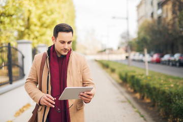 Sticker - Businessman standing on the street and hold his tablet.