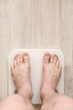 © koldunova - Male bare feet stand on smart scales that makes bioelectric impedance analysis, BIA, body fat measurement. Copy space.