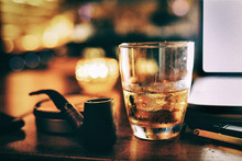 Close-up Of Alcohol In Glass By Smoking Pipe On Table
