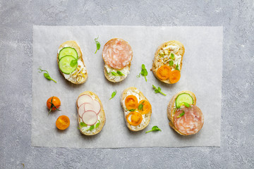 Wall Mural - Toasts with cucumber, tomatoes, cream cheese, salami and fresh salad, top view. Healthy, organic food concept