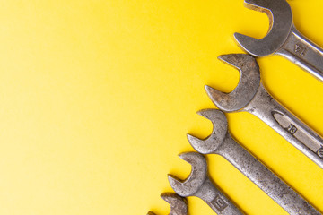 Old dirty wrenches on a yellow background. From above. Copy space