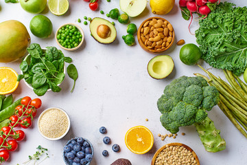 Creative flat lay with healthy vegetarian meal ingredients. Raw food concept. A variety of organic fruits, nuts, berries and vegetables with avocado. Vegan menu frame with copy space.