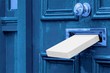 Sending a Gift In The Post.Postal box the parcel is delivered through the parcel door opening.White post box, old aged grunge blue wooden door.Delivery of parcels during the period of self-isolation.
