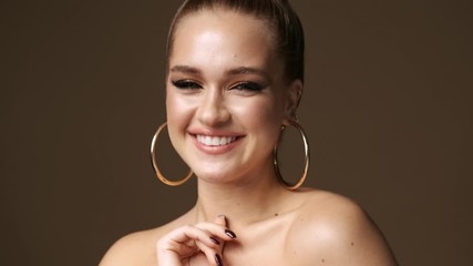 Sticker - A flirty young half-naked woman wearing stylish earrings is laughing isolated over the beige background in studio