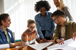 © BalanceFormCreative - Group of design students sitting in classroom and examining blueprint homework project.