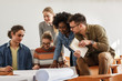 © BalanceFormCreative - Group of design students sitting in classroom and examining blueprint homework project.