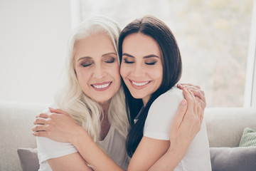 Wall Mural - Close-up portrait of two nice attractive lovely cheerful dreamy women mom daughter granny granddaughter hugging enjoying holiday daydream in house apartment indoors