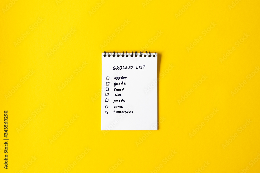 Grocery list paper notepad on yellow background with copy space, top view - obrazy, fototapety, plakaty 
