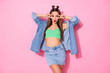 © deagreez - Photo of pretty funky tempting lady showing v-sign symbols near eyes blowing air kisses wear denim jacket green crop top short skirt isolated pastel pink color background