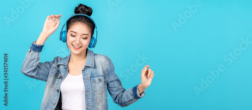 Young happy attractive asian woman using headphone enjoy listen to song in concept of next normal life, pastime or hobby online Tableau sur Toile