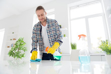 Low Angle View Photo Of Positive Guy Do Household Chores Want Disinfection Kitchen Table Use Chemical Cleaner Spray Wash Rag Wear Casual Checkered Outfit Indoors