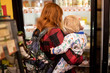 © Дмитрий Чапурин - A mother holds a baby in her arms at a grocery store.