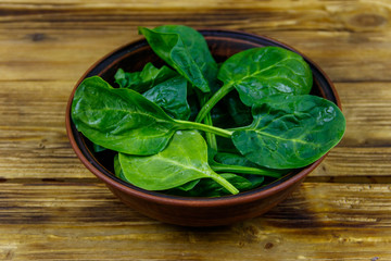 Poster - Fresh green spinach leaves in bowl on a wooden table