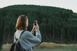 © bodnarphoto - Pretty girl sitting on the apartment terrace on the background of mountain landscape and lake, using a smartphone with a serious face. Girl tourist uses internet on smartphone on balcony in mountain