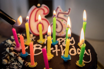 Lighting Happy Birthday Cake Candles. Chocolate Cake 65th Birthday Party Celebration