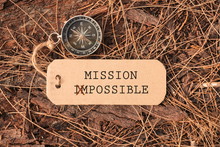 Magnetic Compass And Paper Tag With Words Mission Impossible Changed To Mission Possible At Outdoor. Conceptual Image With Selective Focus