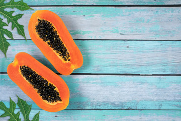 Top view ripe holland papaya sliced with leaves on vintage wooden table background with copy space