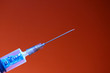 Syringe with a chip on a red background, toned. The concept of the theory of conspiracy and implantation of vaccinated chips. Global control of humanity.