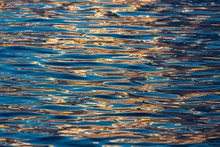 The Surface Of The Water In The Sea, With Gentle Ripples, Reflecting The Morning Sun Until It Creates Beautiful Color Streaks.