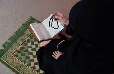 Wall Mural - Middle eastern woman praying and reading the holy Quran