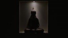 Lights Reveal Meditating Buddha Statue In Alcove In Darkness