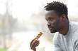© PheelingsMedia - Serious black man with snack bar and coffee in a park