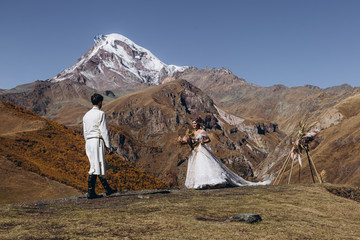 Wall Mural - dynamic wedding photo of brides at the top of the mountain, happy loving couple hugging and kissing during wedding photo session