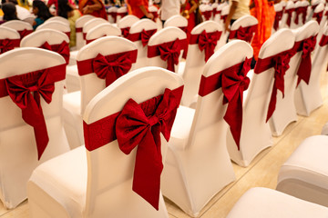 Wedding chairs decorated with a red bow at a banquet hall