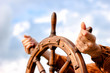 canvas print picture - Steering hand wheel ship on sky background, hand hold hand wheel