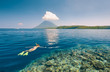 © soft_light - Woman snorkeling in clear tropical waters on a background of island