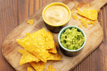 Tortilla Chips Nachos, Sauce Guacamole And Cheese Sauce On Wooden Background