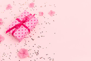 Wall Mural - Gift box, flowers and gold confetti on pink background. Spring, summer Holidays, Birthday, Mothers Day. Copy space. Flat lay.