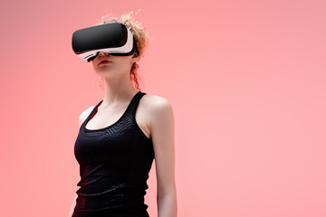 Wall Mural - young woman in in sportswear and virtual reality headset on pink