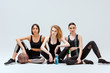 © LIGHTFIELD STUDIOS - multicultural girls sitting with sport equipment on white