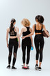 © LIGHTFIELD STUDIOS - back view of multicultural women standing with sport equipment on white