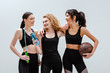© LIGHTFIELD STUDIOS - cheerful and multicultural girls standing with sport equipment isolated on white