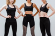 © LIGHTFIELD STUDIOS - cropped view of multicultural women in sportswear standing with hands on hips isolated on white